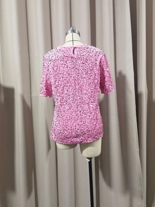 Detail of pink sequin T-shirt featuring a back neck button closure and sparkling texture