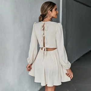 Detail view of the open back with bow ties on a beige long sleeve A-line mini dress