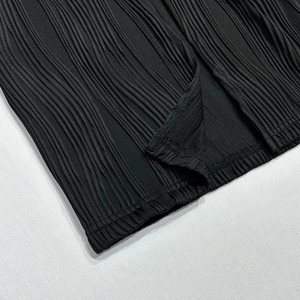 Detail of black pleated fabric texture showing high-quality stitching and crinkle finish