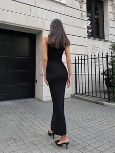 Full back view of a slim fit sleeveless black knitted maxi dress on a model in urban setting