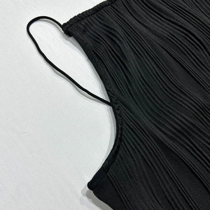 Close-up of black sleeveless dress featuring detailed vertical pleated fabric texture