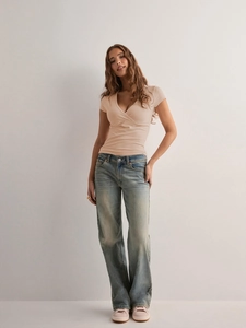 Detail of slim fit V-neck T-shirt in beige paired with light blue distressed denim jeans