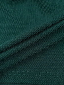 Detailed macro view of dark green waffle fabric texture with neat flat seam stitching