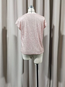 Dettaglio ravvicinato di paillettes rosa chiaro verticali su un top da festa senza maniche
