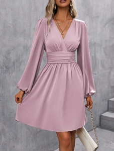 Detail of V-neckline and tiered cinched waist on elegant dusky pink long sleeve dress