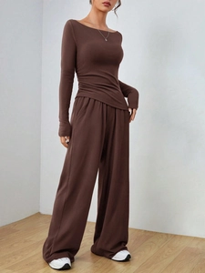 Dettaglio del top marrone scuro a maniche lunghe con arricciature e pantaloni larghi