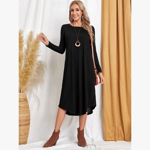 Detail of loose black long sleeve knit dress with side pockets and curved hem