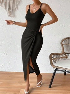 Détail d'une robe en maille côtelée noire avec nœud à la taille et fente haute