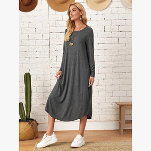 Detail of loose dark grey long sleeve dress showing side pocket and curved hemline