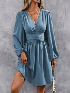Detailed view of the deep V-neckline and high-waisted pleated design on a blue dress