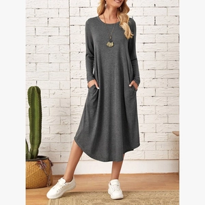 Detail view of the side-seam pockets and curved hem on a loose-fit knit long sleeve dress