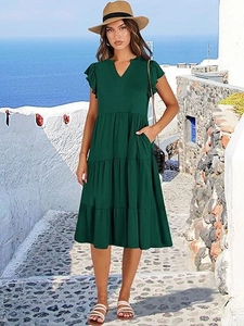 Dettaglio dell'abito lungo verde scuro con scollo a V, maniche a volant e balze