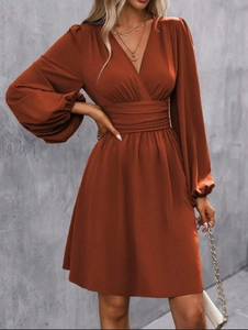 Detail of dark orange V-neck wrap dress with lantern sleeves and pleated high waist band