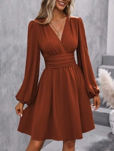 Detail view of brick red V-neck mini dress featuring lantern sleeves and pleated waist design