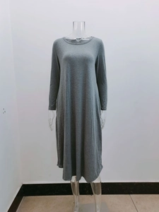 Detail of the mid-gray knit dress showing the round neck, side pockets, and curved hem