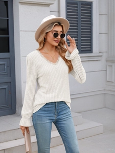 Detail of V-neck lace trim and ribbed texture on white long sleeve knit top