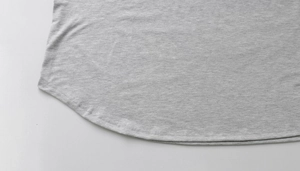 Detailed view of the curved hem and fine stitching on a grey knit long sleeve dress