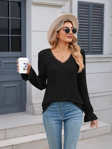 Detailed view of women's black ribbed knit top featuring lace V-neck and ruffled cuffs