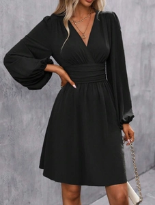Detail of cross deep V-neckline and high-waisted pleated design on black long sleeve dress