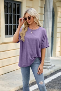 Outdoor street style view of a loose purple crewneck T-shirt paired with blue ripped jeans