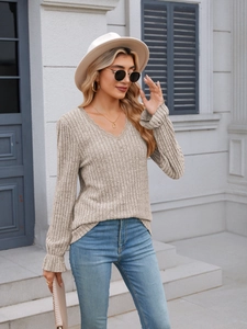Detail of V-neck with lace trim and ribbed knit texture on beige long sleeve top