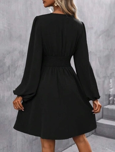 Detail view of the black long sleeve dress featuring an elastic smocked waist design
