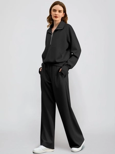 Detail of black two-piece sports tracksuit featuring half-zip collar and wide-leg trousers