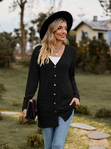Close-up of black ribbed knit cardigan with wooden buttons and front pockets in garden