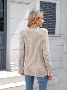 Detailed view of beige ribbed knit top with lace V-neckline and ruffled sleeve cuffs