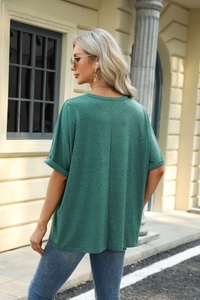 Detail showing the vertical back seam and rolled cuffs of the dark green loose t-shirt