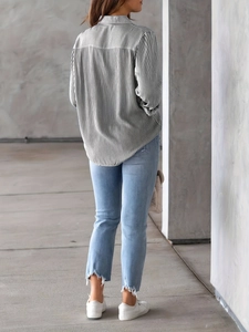 Back view of a loose black and white striped long sleeve shirt with blue denim jeans