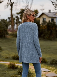 Detail of grey ribbed knit cardigan texture on a female model in an outdoor garden setting