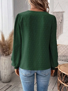 Back view of dark green Swiss dot V-neck top with long sleeves in a cozy indoor setting