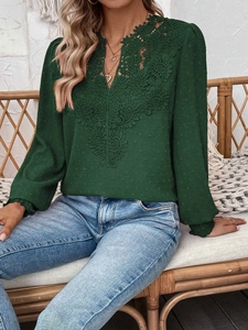 Detailed view of dark green Swiss dot fabric with intricate lace embroidery on V-neckline