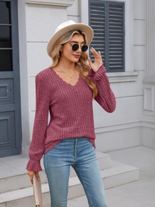 Detail of pink ribbed knit top showing V-neck lace trim and elegant ruffle cuffs