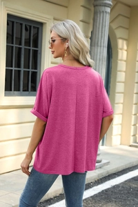 Detail of rose red loose T-shirt featuring back seam and rolled cuffs in street setting