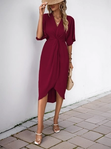 Detail of burgundy V-neck dress with waist knot and asymmetrical tulip hemline
