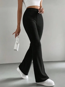 Women's black high-waisted ribbed knit flare pants styled with white tank top and sneakers