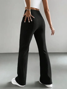 Detail showing the vertical rib texture of black high-waisted flared knit trousers