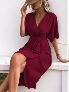 Detail of deep red V-neck dress featuring a stylish waist knot and side slit