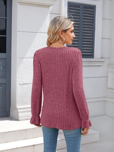 Detailed texture of ribbed rose pink sweater with elegant lace neckline and ruffled cuffs