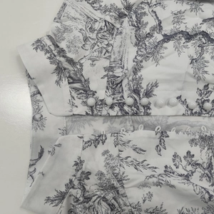 Detail of Toile de Jouy print dress with white dome buttons and classic collar design