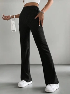 Detail view of high-waisted ribbed knit flare trousers in black with a premium drape