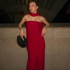 Elegant red off-shoulder mermaid dress with matching neck scarf and black woven handbag