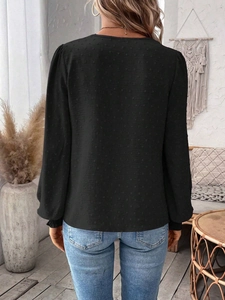 Detail of black long-sleeved top featuring textured swiss dot fabric and puff sleeves