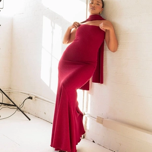 Detail view of red ribbed knit fabric and elegant fishtail hem on slim fit maxi dress