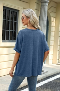Detail of greyish-blue loose fit T-shirt showing rolled sleeves and textured knit fabric