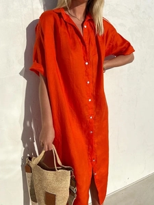 Detail of bright orange cotton linen shirt dress featuring white buttons and textured fabric