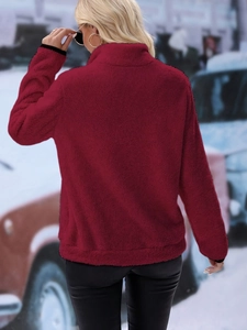 Detailed back view of a burgundy plush half-zip fleece jacket in a snowy winter setting