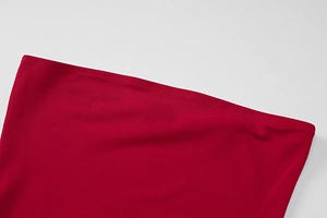 Detailed view of the dark red ribbed fabric and precise double-needle hem on a fitted dress